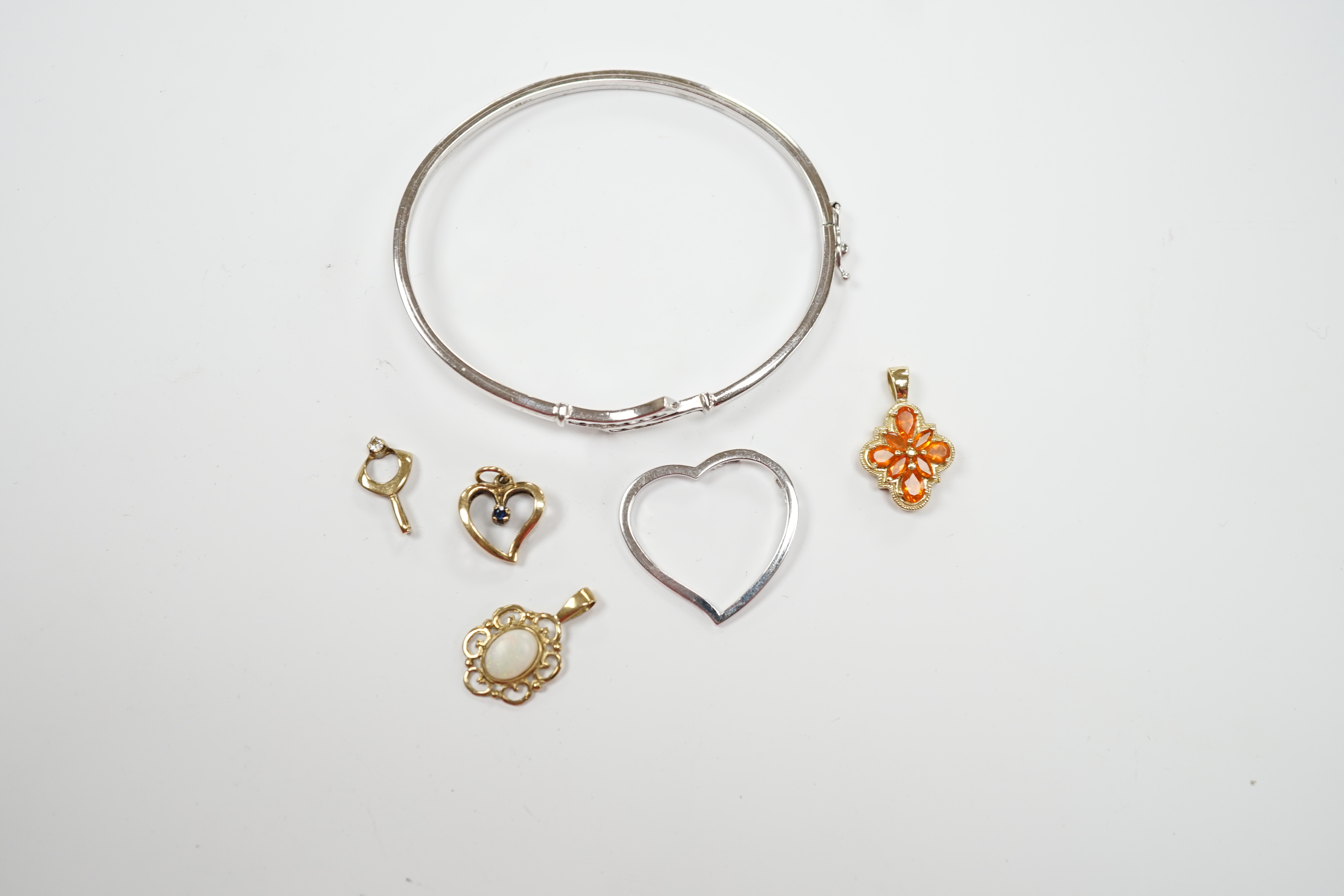 A 9ct white gold heart pendant, a 9kt bangle, two 9ct and gem set pendants and two yellow metal pendants.